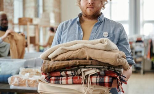 A man holding blankets at a community volunteer event, indoors, during the day.